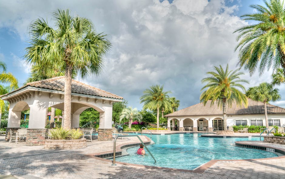 Beautiful tropical resort poolside scene featuring palm trees and inviting water under a cloudy sky