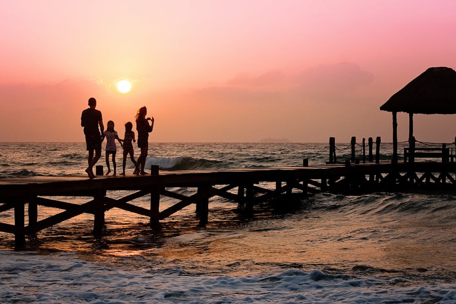 Silhouetted family enjoys a stroll on the beach pier at a vibrant sunset over the ocean waves